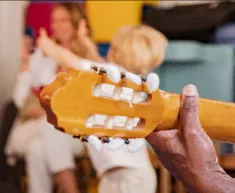 Une personne joue de la guitare devant des enfants qui dansent