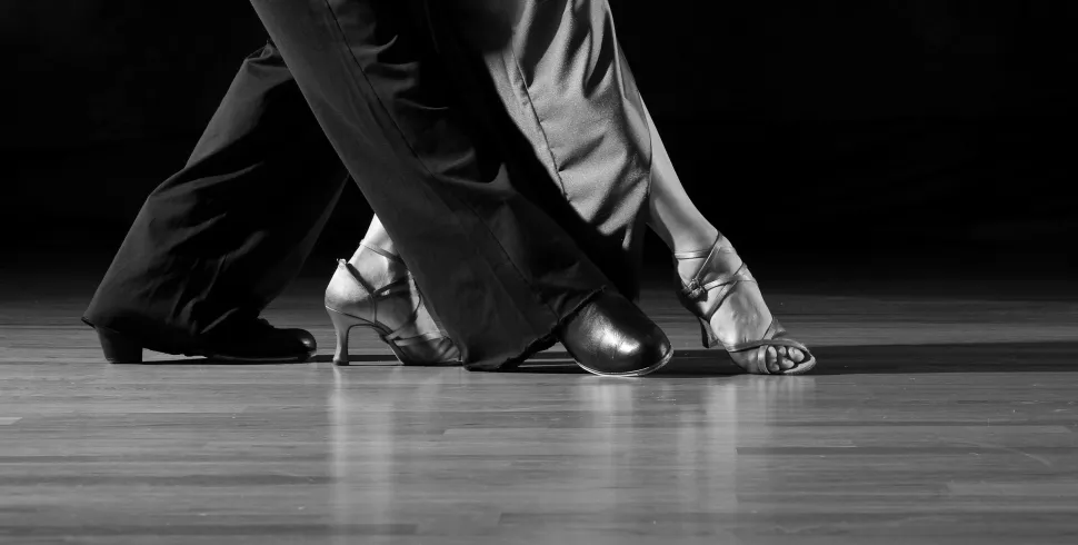un homme et une femme effectuent un pas de danse, chaussures à talons, photo noir et blanc © 