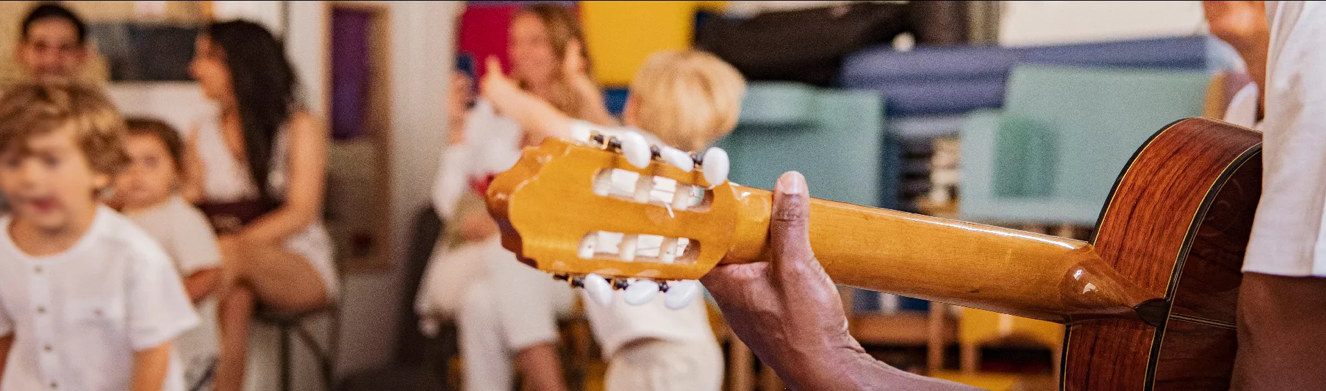 Une personne joue de la guitare devant des enfants qui dansent © 